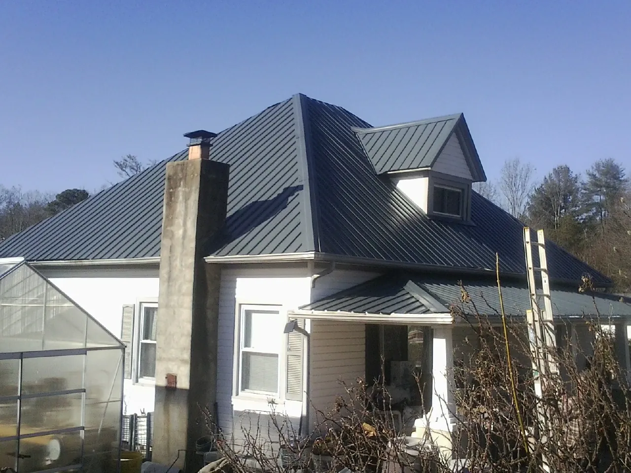 Dark blue standing seam metal roof on a white farmhouse with dormer — Slate & Tile Roof Repair by Roofing Brothers in Fernwood