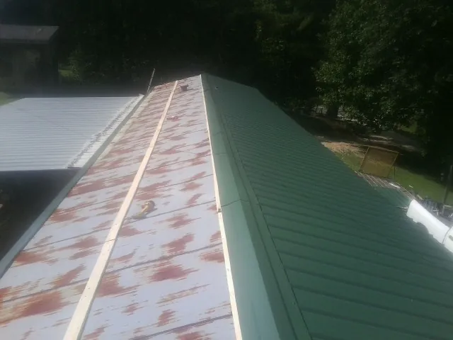 Old rusted panels beside newly installed green metal roofing — Wind Damage Roof Repair by Roofing Brothers in Fernwood