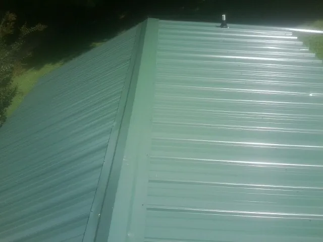 New green metal panels meeting at the ridge of a roof — Flat Roof Repair work by our crew in Fernwood