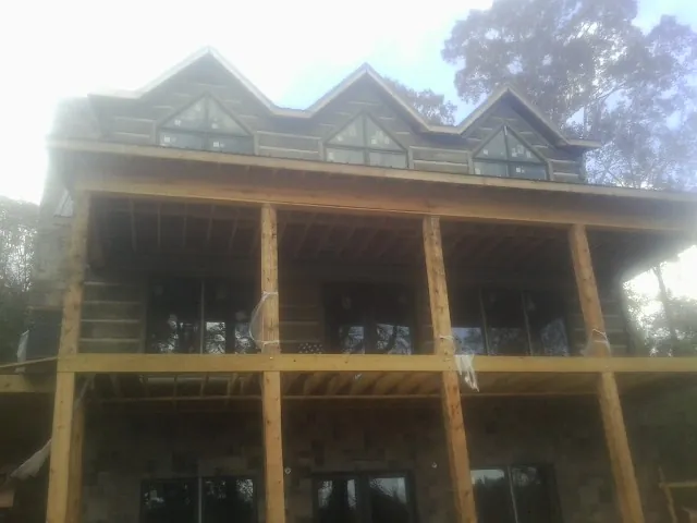 Dormers and porch framing on a large log home under construction — Roof Coating work by our crew in Fernwood