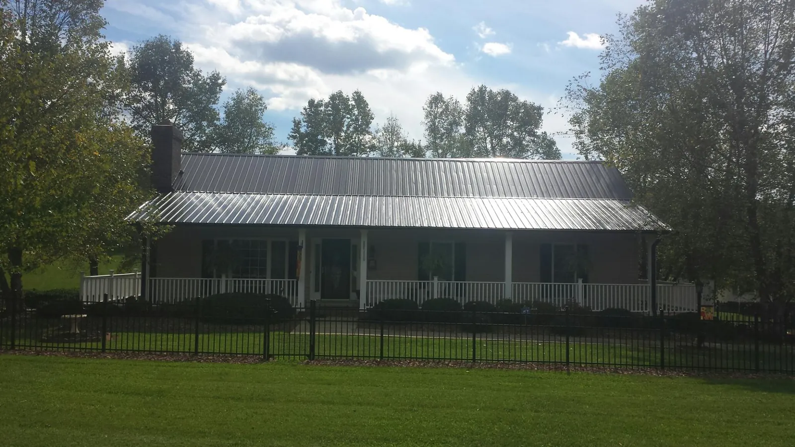 Gray metal roof on a brick ranch with a full width front porch — Gutter Guard Installation work by our crew in Fernwood