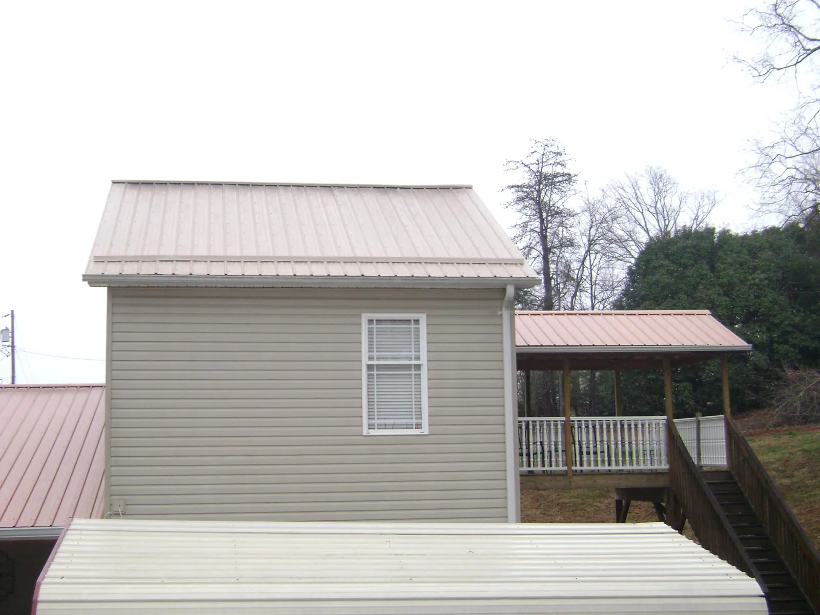 Tan metal roofs on a two story addition and attached porch, from a Roof Replacement job in Fernwood