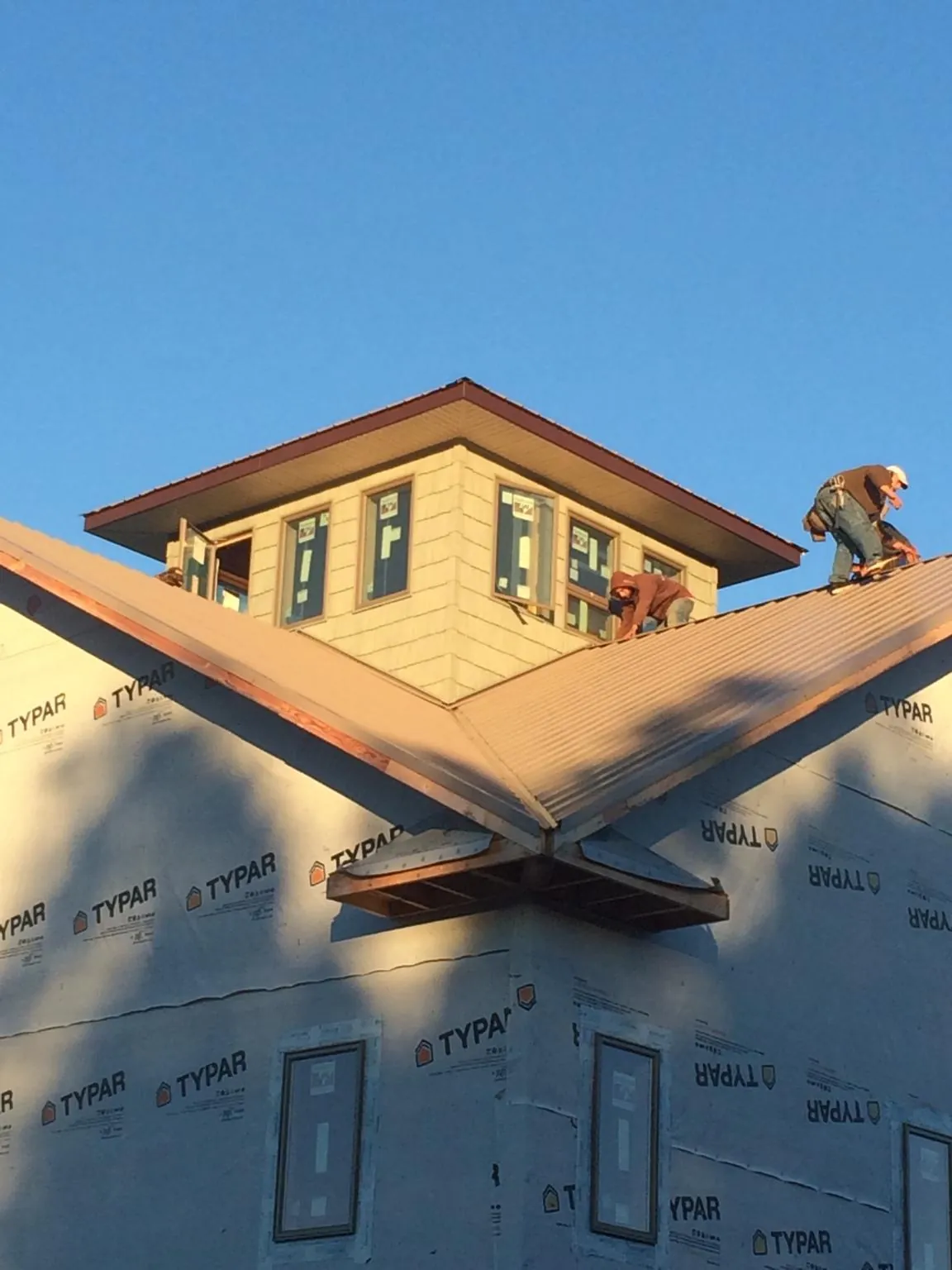 Roofers working around a rooftop cupola on a new metal roof at sunset — Roof Waterproofing in Fernwood by Roofing Brothers